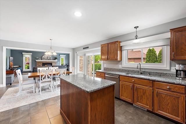 kitchen with a sink, dishwasher, light stone countertops, and a center island