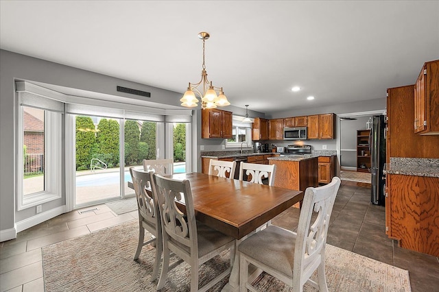 tiled dining space featuring a chandelier, recessed lighting, baseboards, and a sink