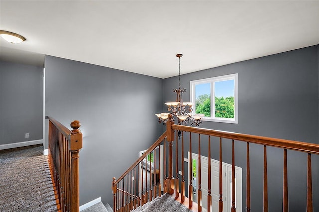 stairway with a chandelier, carpet floors, and baseboards