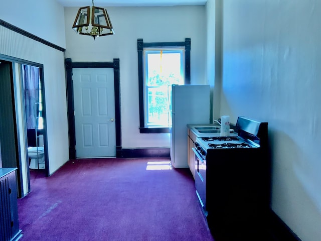 103 W Michigan Ave, Clinton, MI 49236 - kitchen with gas range oven, dark carpet, a chandelier, a sink, and hanging light fixtures