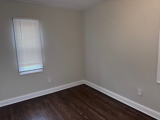 unfurnished room featuring baseboards and dark wood-style flooring