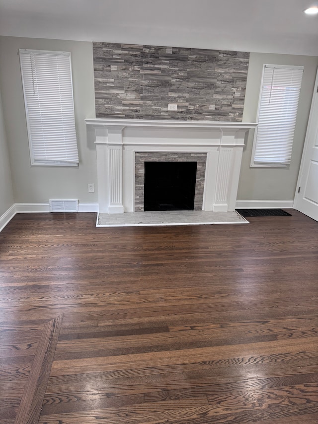 unfurnished living room featuring a large fireplace, baseboards, and dark wood-style floors
