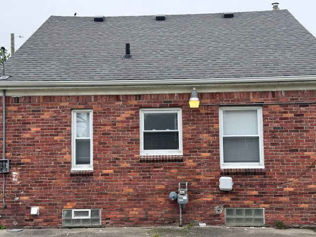 view of property exterior with a shingled roof and brick siding