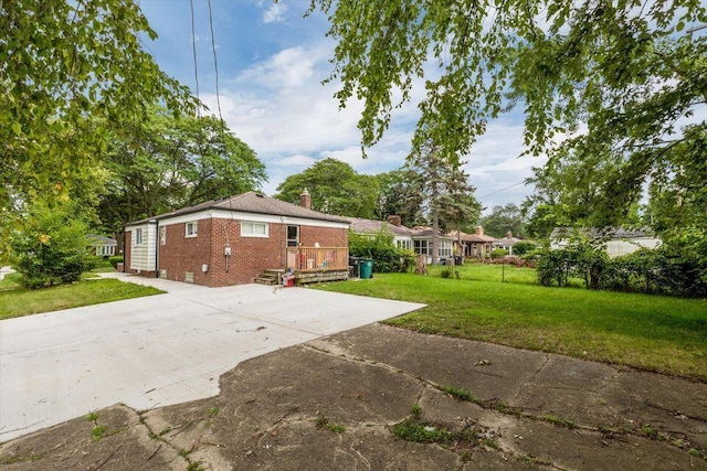 view of side of property with brick siding, a chimney, and driveway