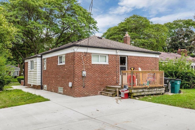 rear view of house with a patio, a chimney, brick siding, and a deck