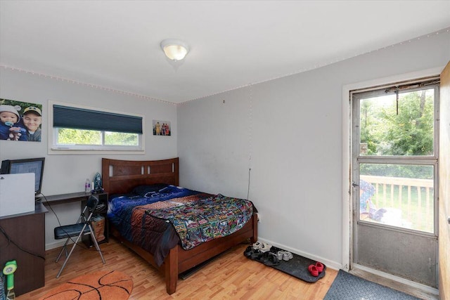 bedroom with wood finished floors, multiple windows, and baseboards