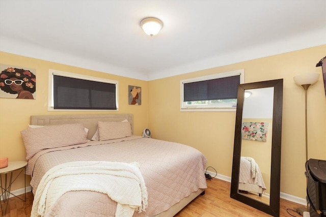 bedroom featuring light wood finished floors and baseboards