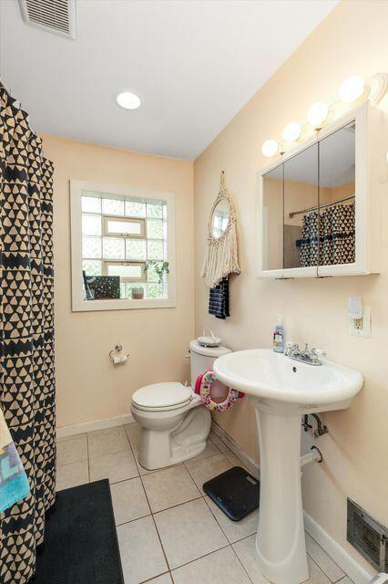 bathroom with baseboards, tile patterned floors, toilet, and curtained shower