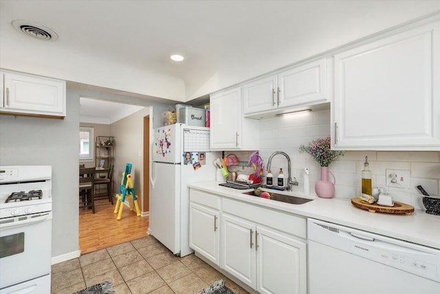 kitchen with white appliances, a sink, white cabinetry, light countertops, and tasteful backsplash
