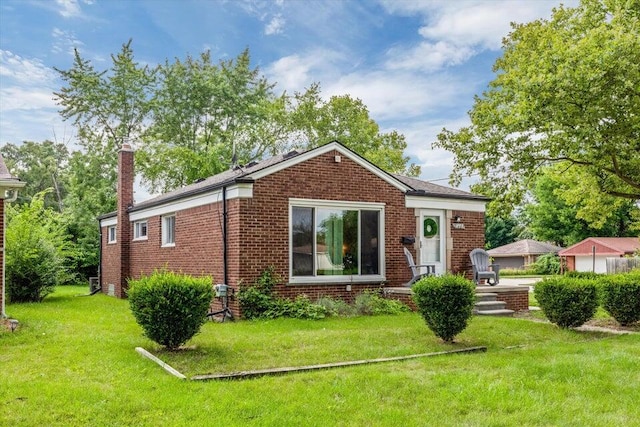 view of front of home with brick siding, a front lawn, and a chimney
