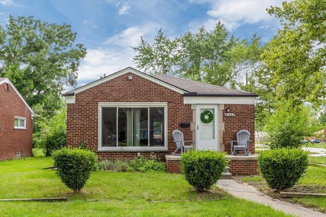 view of front of house featuring brick siding, a front lawn, and a porch