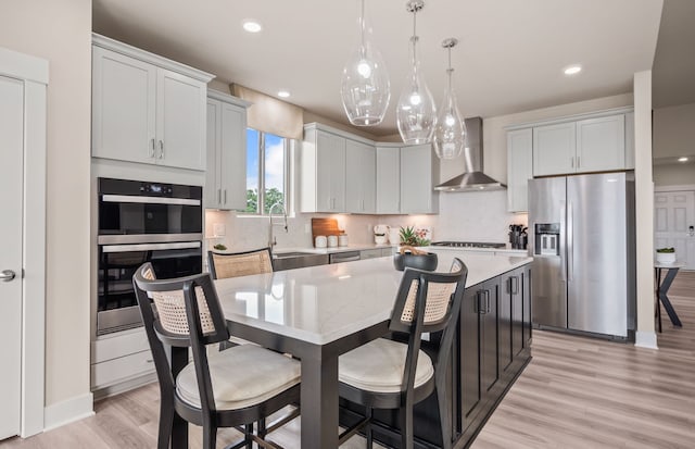 3048 Sheffield Cir, Clarkston, MI 48346 - kitchen with appliances with stainless steel finishes, wall chimney exhaust hood, light wood-type flooring, backsplash, and a kitchen island