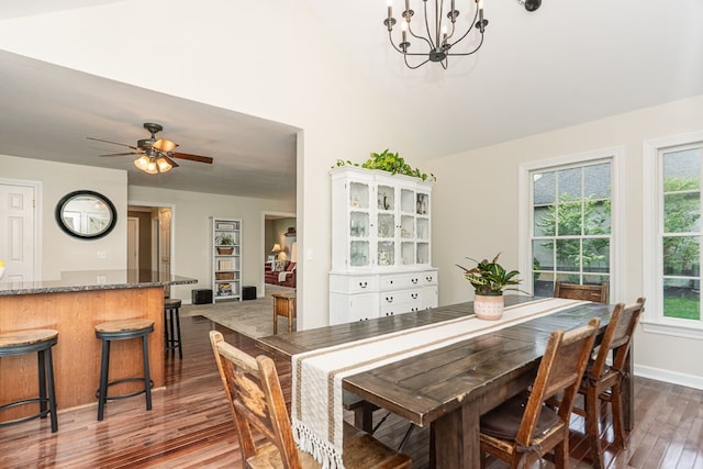 dining space with wood finished floors, a chandelier, a ceiling fan, baseboards, and high vaulted ceiling