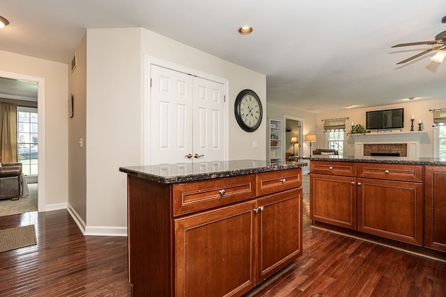 kitchen featuring open floor plan, ceiling fan, dark wood-type flooring, a fireplace, and recessed lighting
