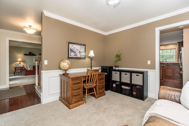 office featuring a sink, crown molding, wainscoting, carpet floors, and wood finished floors