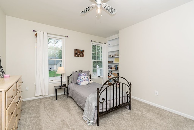 bedroom featuring light colored carpet, baseboards, multiple windows, and ceiling fan