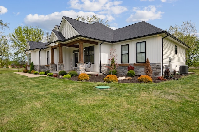 view of front of house featuring stone siding, a front lawn, a shingled roof, central air condition unit, and a porch