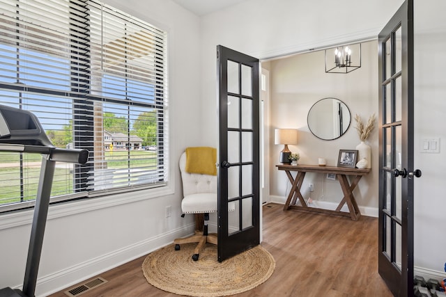 living area with french doors, a chandelier, baseboards, and wood finished floors