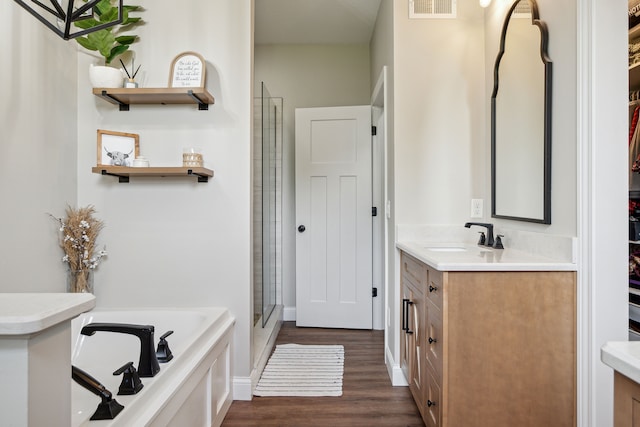full bathroom featuring vanity, wood finished floors, a garden tub, and a stall shower