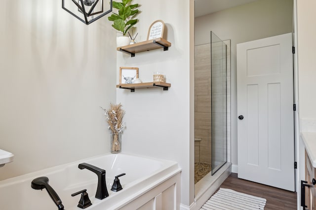 bathroom featuring a garden tub, a tile shower, and wood finished floors