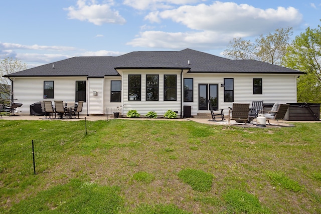 back of house with a patio area, a hot tub, a lawn, and roof with shingles