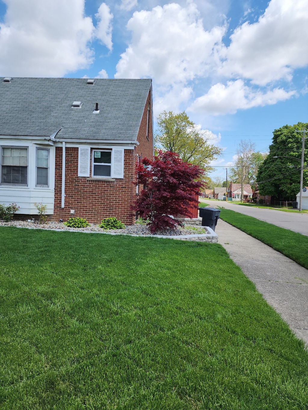 9006 Grandville Ave, Detroit, MI 48228 - view of side of property with roof with shingles, brick siding, and a lawn