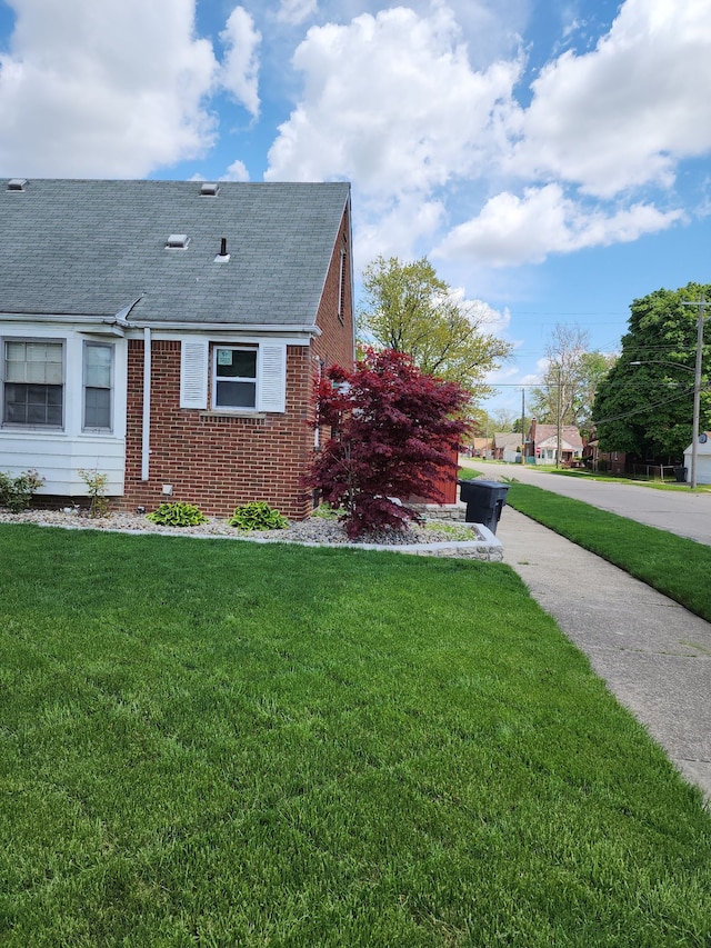 9006 Grandville Ave, Detroit, MI 48228 - view of side of property with roof with shingles, brick siding, and a lawn