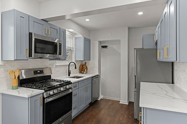 kitchen with appliances with stainless steel finishes, a sink, tasteful backsplash, light stone counters, and recessed lighting