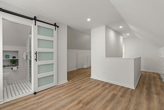 bonus room featuring a barn door, vaulted ceiling, recessed lighting, wood finished floors, and baseboards