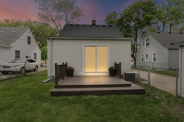 back of house at dusk featuring a wooden deck, a chimney, and central AC unit