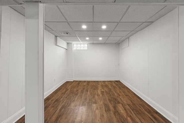 basement with dark wood-style floors, recessed lighting, baseboards, and a drop ceiling