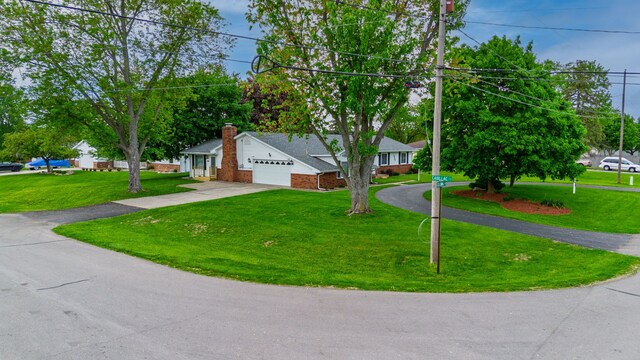 6934 Colonial Dr, Tecumseh, MI 49286 - view of front facade with concrete driveway, an attached garage, a front lawn, brick siding, and a chimney