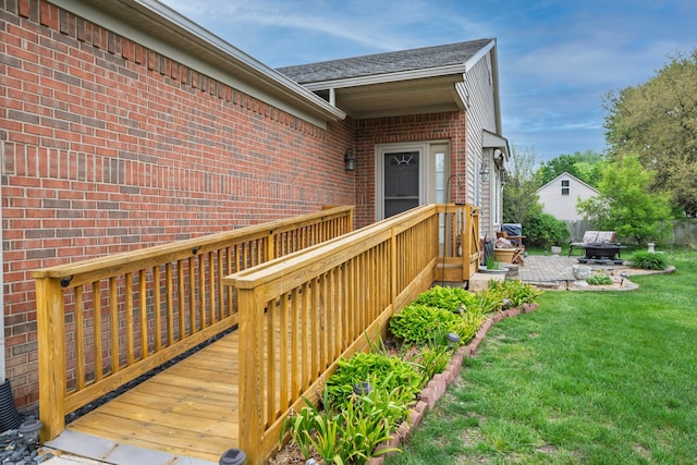 entrance to property with a wooden deck, a yard, and brick siding