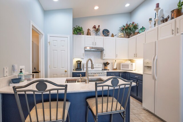 kitchen with white appliances, under cabinet range hood, blue cabinets, white cabinets, and recessed lighting