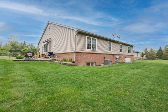 back of property with cooling unit, a yard, a patio, and brick siding