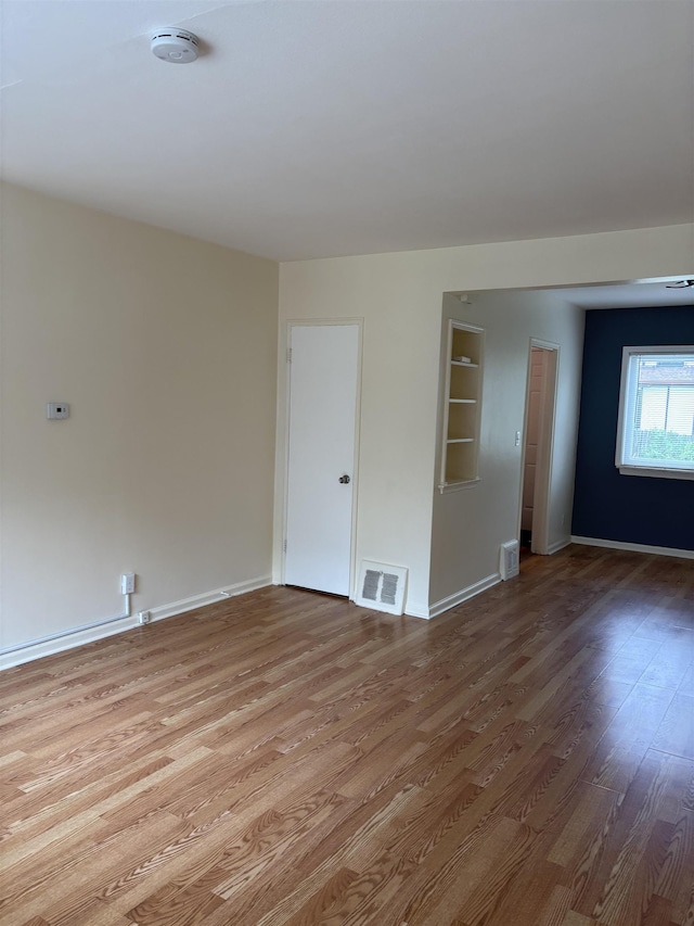 unfurnished room with wood finished floors, a smoke detector, and baseboards