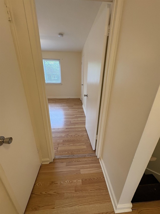 hallway featuring light wood-style flooring and baseboards