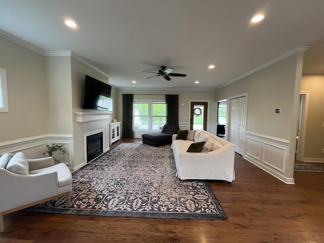 living room with a glass covered fireplace, crown molding, wainscoting, ceiling fan, and recessed lighting