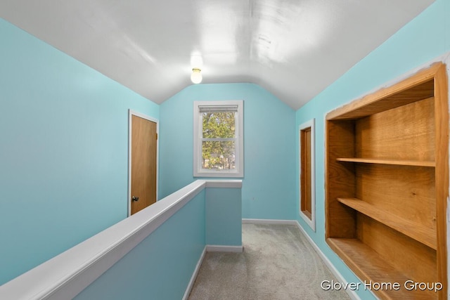 hallway with carpet floors, lofted ceiling, and baseboards