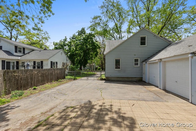 view of home's exterior with fence, a garage, driveway, and a shingled roof
