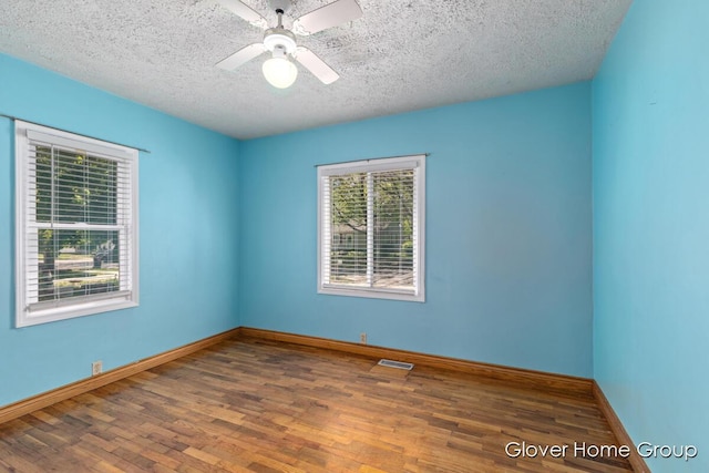 spare room featuring a textured ceiling, wood finished floors, baseboards, and a ceiling fan