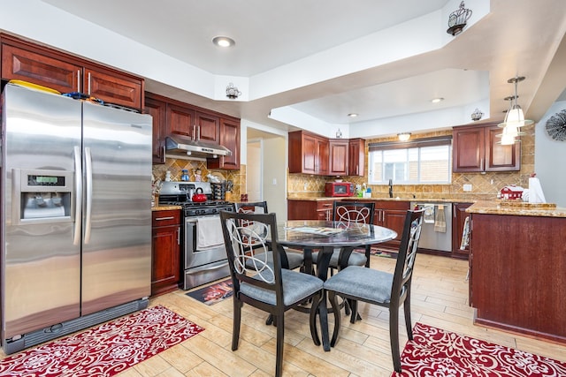 12848 E 14 Mile Rd, Warren, MI 48088 - kitchen featuring appliances with stainless steel finishes, under cabinet range hood, light wood finished floors, and decorative backsplash