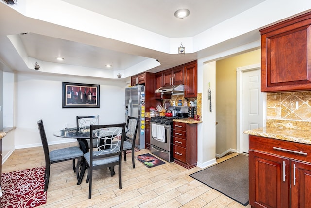 12848 E 14 Mile Rd, Warren, MI 48088 - kitchen with appliances with stainless steel finishes, under cabinet range hood, a tray ceiling, light wood-type flooring, and tasteful backsplash