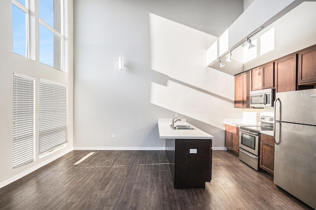 600 Douglas St NW Unit 600C, Grand Rapids, MI 49504 - kitchen with appliances with stainless steel finishes, rail lighting, dark wood-type flooring, baseboards, and a sink