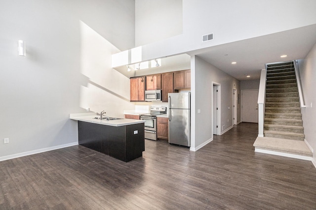 600 Douglas St NW Unit 600C, Grand Rapids, MI 49504 - kitchen featuring stainless steel appliances, a peninsula, a towering ceiling, baseboards, and dark wood finished floors