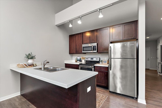 600 Douglas St NW Unit 600C, Grand Rapids, MI 49504 - kitchen with stainless steel appliances, rail lighting, a sink, dark brown cabinetry, and wood finished floors