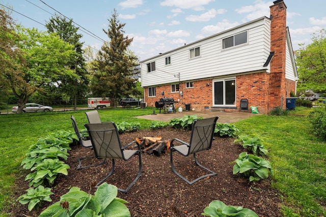 rear view of house featuring brick siding, a patio area, a chimney, and an outdoor fire pit