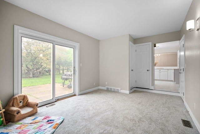 empty room featuring a chandelier, light colored carpet, and baseboards