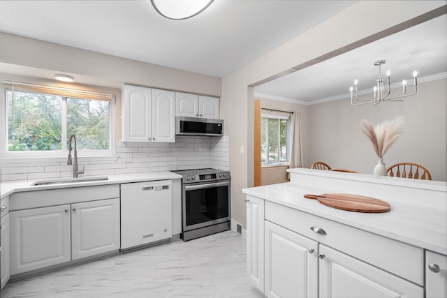 kitchen with stainless steel appliances, a sink, a chandelier, decorative backsplash, and white cabinets