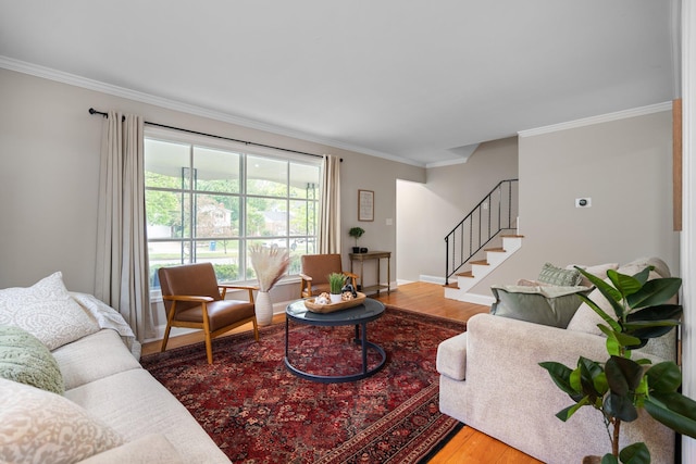 living area featuring stairway, crown molding, wood finished floors, and baseboards